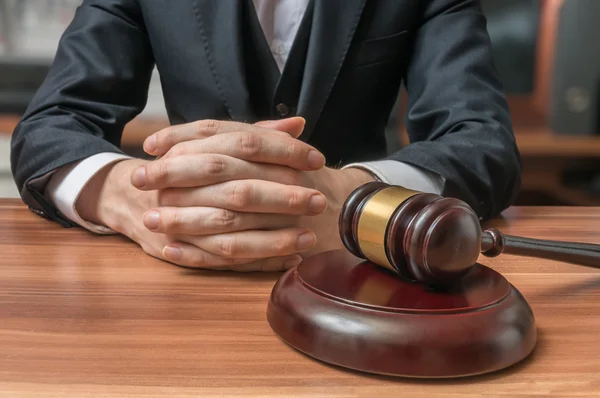 Advocaat heeft gevouwen handen en hamer op de voorgrond. Justitie en wet concept — Stockfoto