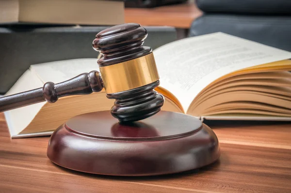 Houten hamer en geopende boek in de achtergrond. Recht en justitie concept — Stockfoto