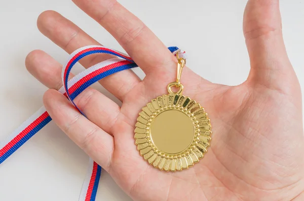 Mens houdt gouden medaille in de hand. — Stockfoto