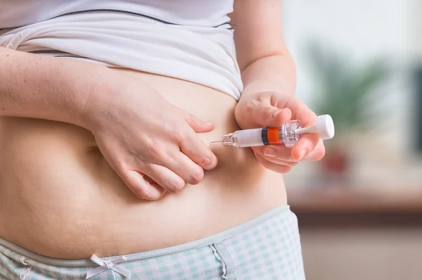 Concepto de anticoagulantes. Mujer está inyectando heparina inyectable en el vientre con jeringa . — Foto de Stock