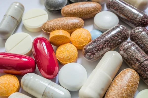 Macro de muitas pílulas coloridas e drogas no fundo branco . — Fotografia de Stock