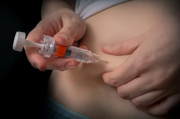 Diabetes and glycemia concept. Patient is injecting insulin injection to belly with syringe. Low key photo. — Stock Photo, Image