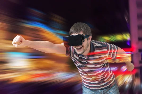 Glücklicher junger Mann spielt Rennvideospiel im 3D-Virtual-Reality-Simulator mit Headset. — Stockfoto