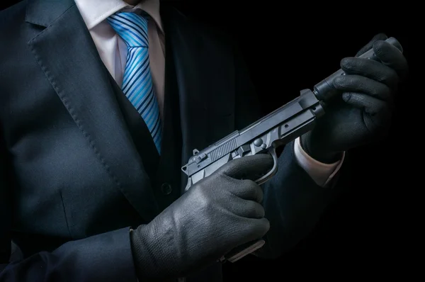 Mafia man or racketeer holds pistol with silincer in hands. Low key photo. — Stock Photo, Image