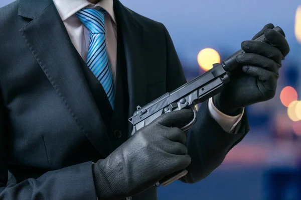 Secret agent holds pistol with silencer in hands at twilight.