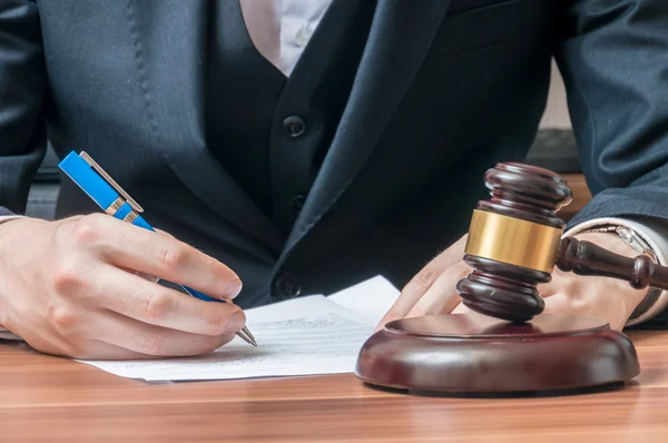 L'avocat écrit sur le document. Gavel en bois devant . — Photo