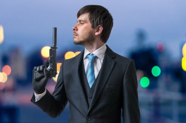 Hitman veya suikastçı tabanca susturucu ile gece karanlığında elinde tutar..