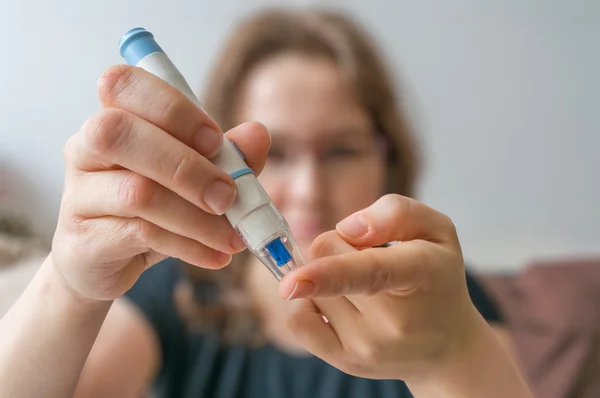 Kvinna använder nål för glukosnivåtest med glukometer. — Stockfoto