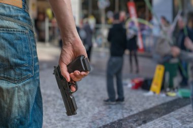 Silah kontrol konsepti. Silahlı adam - saldırgan halka açık bir yerde elinde tabanca tutar. Sokakta birçok kişi.