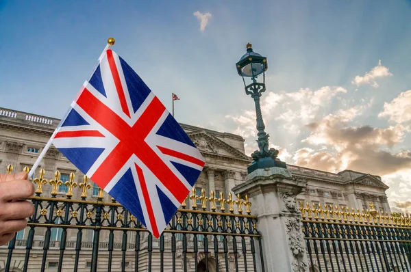 Hand Está Segurando Bandeira Grã Bretanha Buckingham Palácio Fundo — Fotografia de Stock