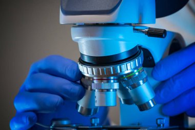 Bilim adamı laboratuardaki mikroskobu ayarlıyor..