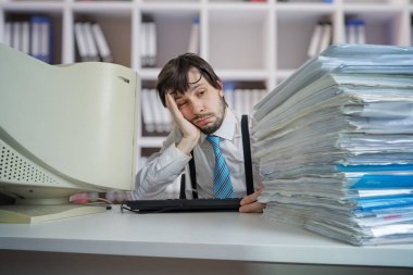 Masasında bir sürü belge olan yorgun ve çok çalışan bir adam. Fazla çalışma ve evrak işi kavramı.