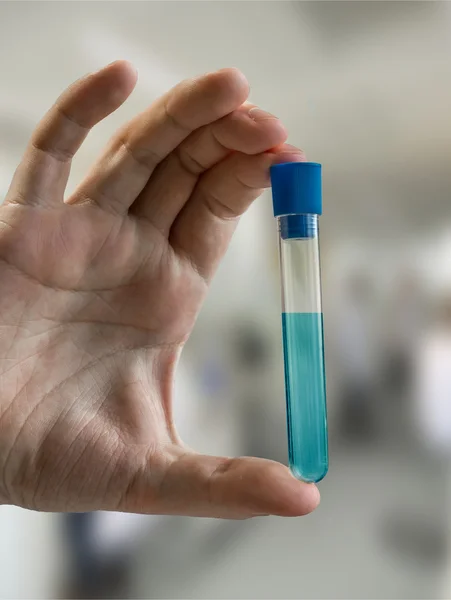 Químico sostiene tubo de ensayo con líquido azul en laboratorio de química — Foto de Stock