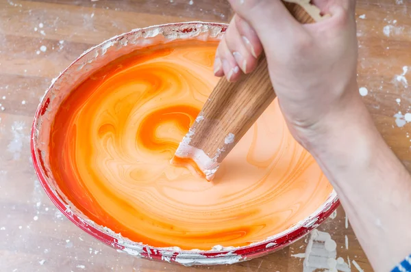 Hand rührt bei Pai Farbe in einem Eimer auf unordentlichem Hintergrund an — Stockfoto