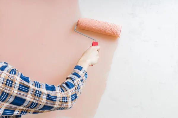 Renovation of interior. Painters hand holds paint roller and pai