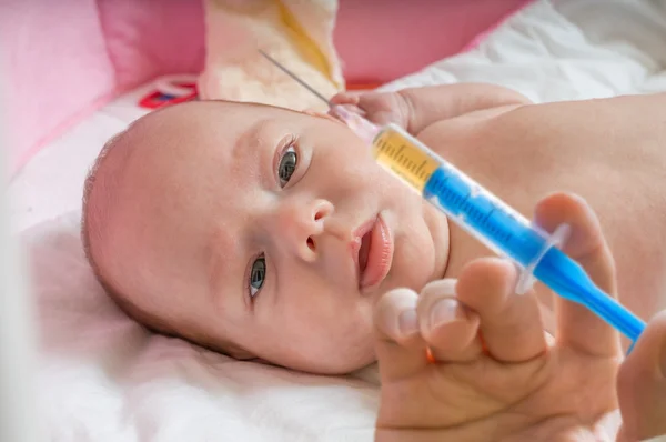 Ill baby is starring on syringe with immunization vaccine Stock Picture
