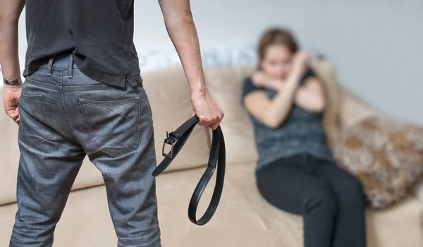 Concepto de violencia doméstica. Ira marido está atacando esposa con cinturón . — Foto de Stock