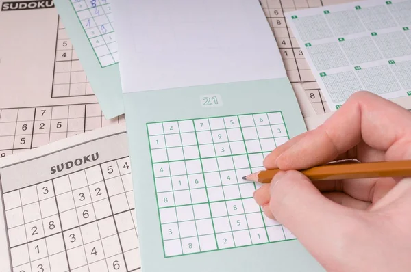 Popular brain teaser logic game sudoku. Hand is writing numbers.