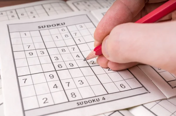 Leere Sudoku-Kreuzworträtsel und Bleistift in der Hand. — Stockfoto