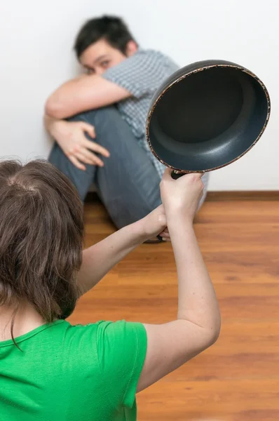 Dominating wife is attacking her henpecked husband with frying pan. — Stock Photo, Image