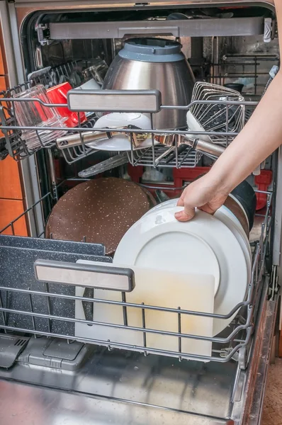 Conceito de trabalho doméstico. Mulher está colocando prato sujo na máquina de lavar louça . — Fotografia de Stock