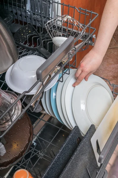 Conceito de trabalho doméstico. Mão feminina está colocando prato sujo na máquina de lavar louça — Fotografia de Stock