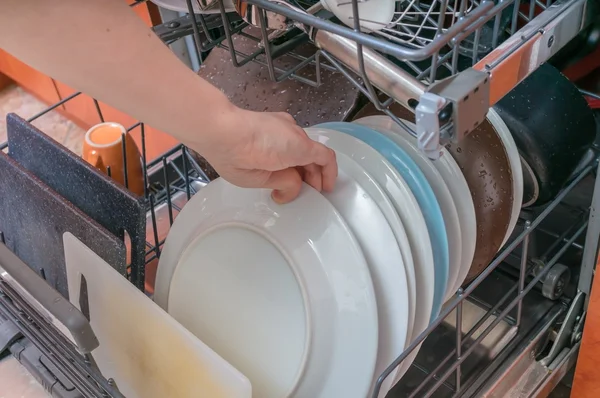 Mão feminina está colocando prato sujo na máquina de lavar louça . — Fotografia de Stock