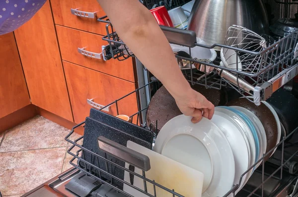 Woman puts dirty dish into dishwasher machine. — Stock Photo, Image