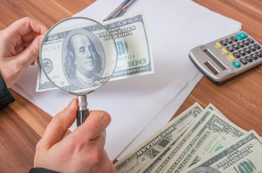 Büyüteç ile taklidini yapmak ya da sahte Doları banknot ile ilgilenen.