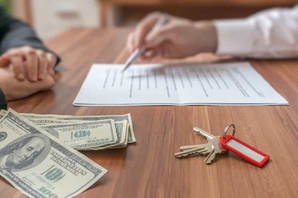 Concepto inmobiliario. Agente inmobiliario que ofrece el contrato para firmar. Dinero y llaves en el escritorio . — Foto de Stock