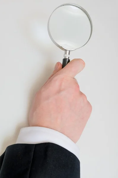 La mano sostiene la lupa. Aislado sobre fondo blanco . — Foto de Stock