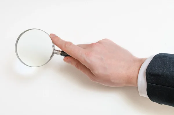 Man in suit holds magnifying glass. Isolated on white background — Stock Photo, Image