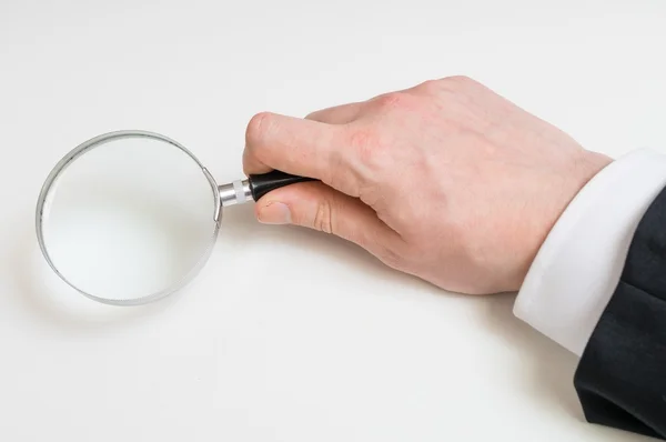 Man in suit holds magnifying glass. Isolated on white background — Stock Photo, Image