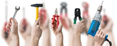 Aletler ve araçlar bulanık arka plan üzerinde birçok eller havaya. 