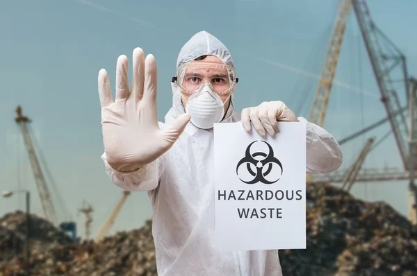 Technician in coverall warns in landfill about hazardous waste. — Stock Photo, Image