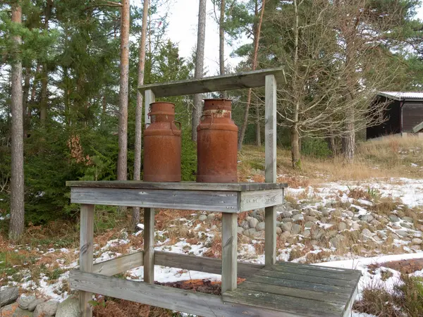 Dvě staré rezavé mléko džbán na lavičce — Stock fotografie