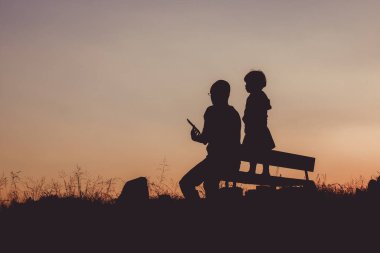 Tepenin alacakaranlığında oturan insanların silueti