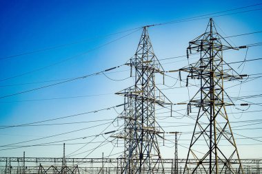 Mavi gökyüzünde parlayan güç iletim kuleleri