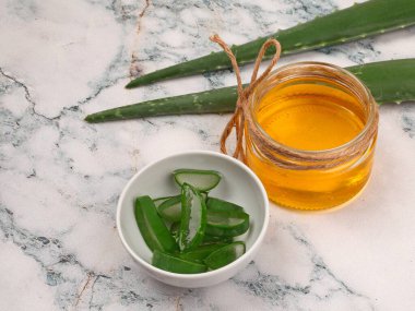 Aloe Vera ve bal, açık mermer arka planda yakın plan. Dilimlenmiş Aloe vera doğal organik yenileme kozmetikleri, alternatif tıp, organik cilt bakımı konsepti
