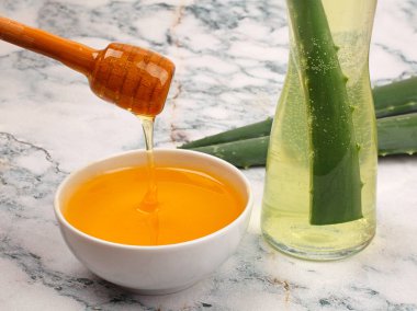 Aloe Vera ve bal, açık mermer arka planda yakın plan. Dilimlenmiş Aloe vera doğal organik yenileme kozmetikleri, alternatif tıp, organik cilt bakımı konsepti
