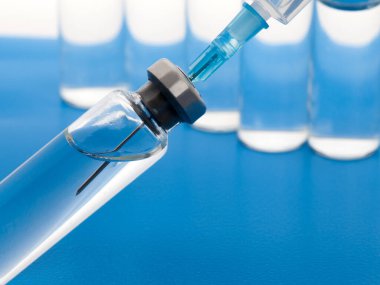 Enjeksiyon için tıbbi şırınga ve ilaç şişelerini kapatın. Mavi arkaplanda