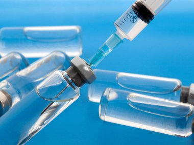 Enjeksiyon için tıbbi şırınga ve ilaç şişelerini kapatın. Mavi arkaplanda