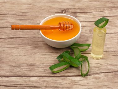 Aloe Vera ve bal, açık ahşap arka planda yakın plan. Dilimlenmiş Aloe vera doğal organik yenileme kozmetikleri, alternatif tıp, organik cilt bakımı konsepti