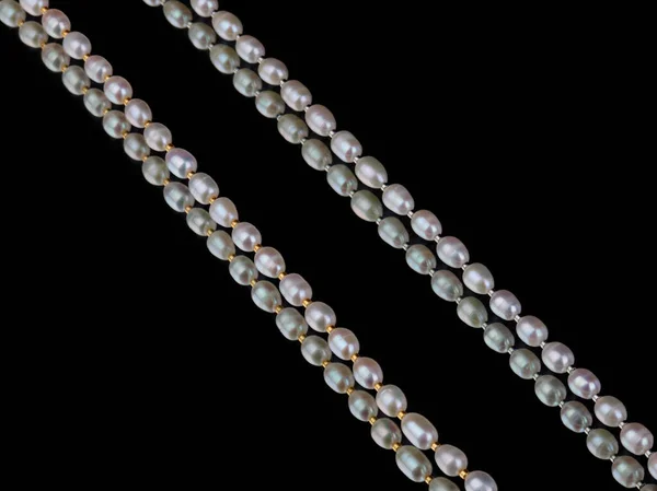 Lines of baroque pearls on black mirror background. With reflection. Close-up shot