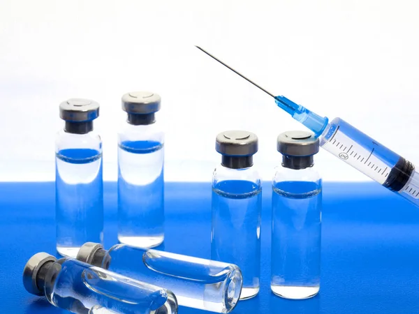 Close-up medical syringe and vials with medicine for injection. On white blue background