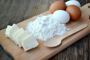 yumurta, tereyağı ve tahta kaşık yemek kartı üzerindeki beyaz un