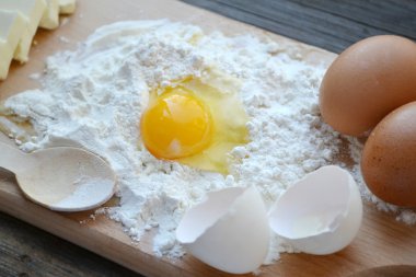 yumurta, tereyağı ve tahta kaşık yemek kartı üzerindeki beyaz un
