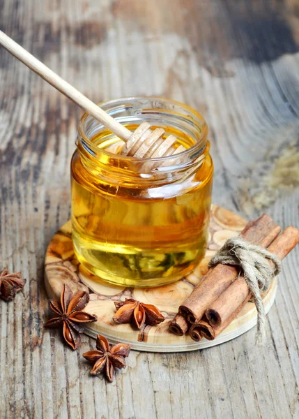 Golden honey with honeystick. cinnamon and anise stars on wooden table — Stock Photo, Image