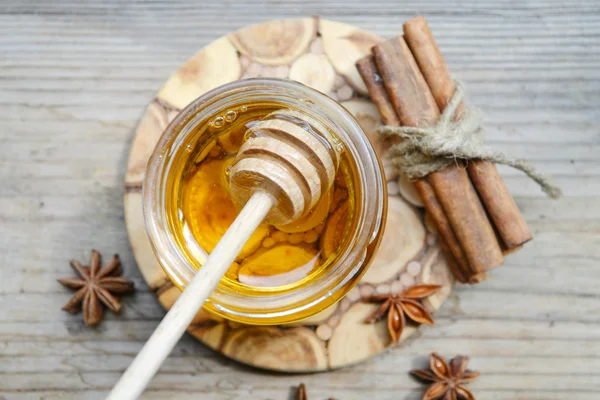 Golden honey with honeystick. cinnamon and anise stars on wooden table — Stock Photo, Image