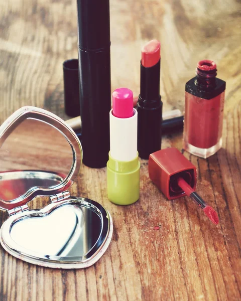 Lindo espejo de bolsillo en forma de corazón con lápiz labial rosa y otros cosméticos en la mesa de madera —  Fotos de Stock